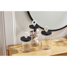 three jars with lids are sitting on a table next to a mirror and some balls