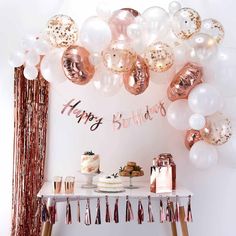 a table topped with balloons and cake next to a sign that says happy birthday on it