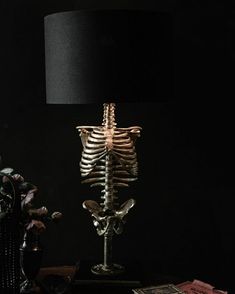 a skeleton lamp sitting on top of a table next to a vase with flowers in it