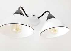 two white lamps with black arms on a white surface