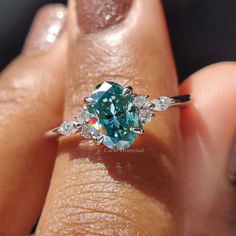 a close up of a person's hand holding a ring with a blue diamond