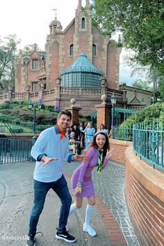 a man and woman posing for a photo in front of a castle at disney world