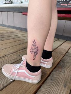 a woman's leg with a flower tattoo on it, sitting on a bench