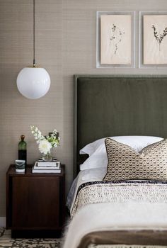 a bedroom with a bed, nightstand and two paintings on the wall above it's headboard