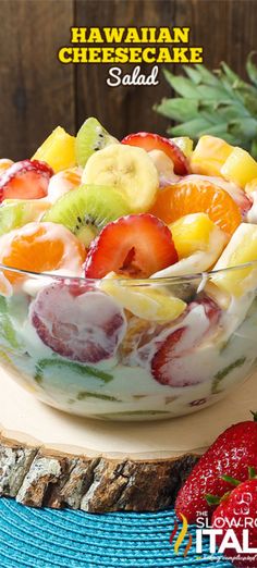 a fruit salad in a glass bowl on top of a wooden table next to pineapples