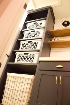 the shelves are filled with baskets and other items in this kitchen cabinetry, which is painted dark gray