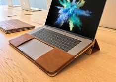 an open laptop computer sitting on top of a wooden table next to a wallet and cell phone