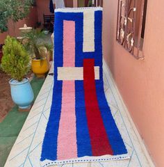 a colorful rug sitting on the side of a building next to a potted plant