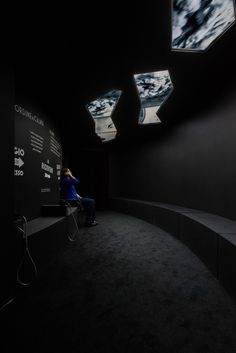 a person sitting on a bench in a room with black walls and lights above them