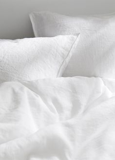 an unmade bed with white sheets and pillows