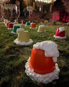 some christmas hats are sitting in the grass near a house with candy canes on it