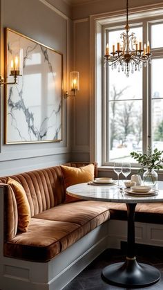 a corner table with two chairs and a bench in front of a large window that has candles on it