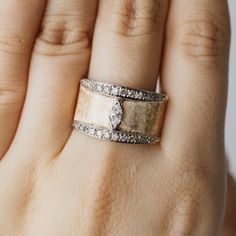 a woman's hand with a gold and silver ring on her left hand, showing the diamond set in the middle