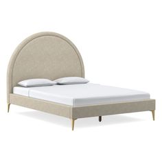 an upholstered bed with white sheets and pillows