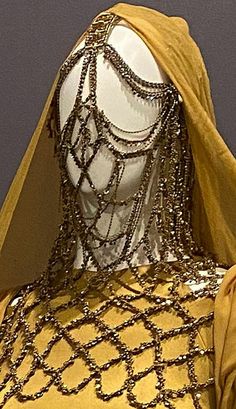 a mannequin wearing a yellow dress with chains on it's neck and head