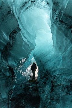 a man standing in an ice cave looking at the water