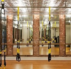 an empty gym room with mirrors and exercise equipment hanging from the ceiling in front of it