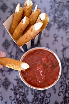 a person is holding some food in their hand and dipping it into a small bowl