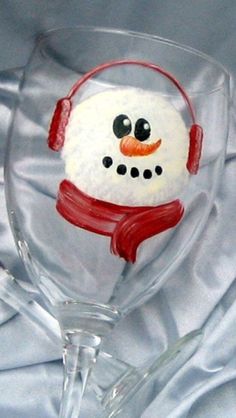 a wine glass with a snowman painted on the side and headphones attached to it