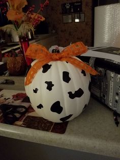 a white pumpkin decorated with black and orange polka dots is sitting on a kitchen counter