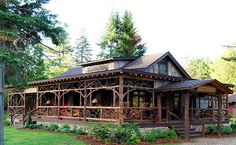 a large wooden house sitting on top of a lush green field next to a forest