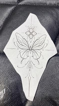 a piece of paper with a butterfly on it sitting on a leather seat cushion in the back of a car