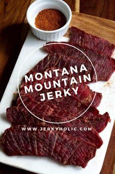 sliced beef sitting on top of a cutting board next to a bowl of seasoning