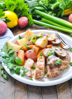 a white plate topped with meat and veggies on top of a wooden table