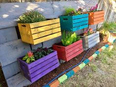 colorful wooden planters are lined up on the side of a fenced in area