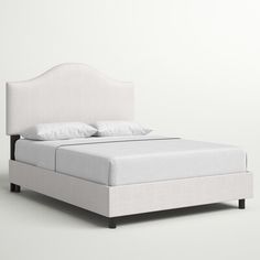 a bed with white linens and pillows on it's headboard is shown