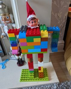 an elf is standing in front of a lego robot made out of multi - colored blocks