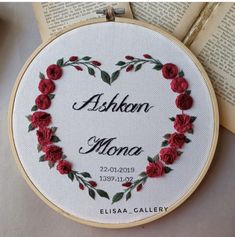 an embroidered heart with red roses and the words ashon mona on it is sitting next to two open books