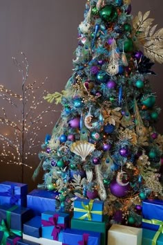 a christmas tree with presents under it and lights on the top is surrounded by blue boxes