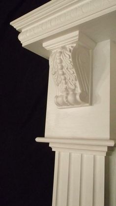 the corner of a white pillar with an ornamental design on it's side and a black background