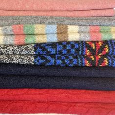 a stack of sweaters sitting on top of each other in different colors and patterns