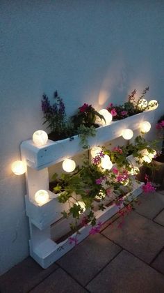 an outdoor planter with lights on it and potted plants in the corner,