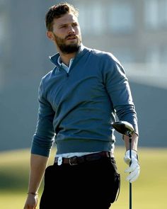 a man holding a golf club while standing on top of a green