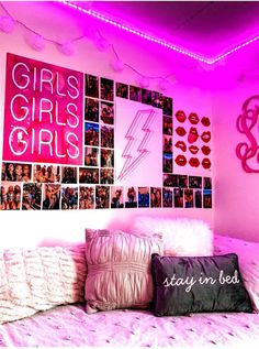 a bedroom with pink lights and pictures on the wall above it, along with pillows