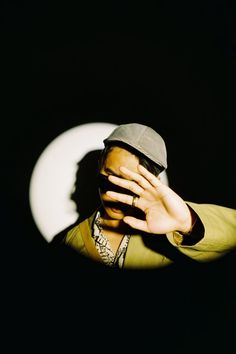 a man covering his face with his hands in front of a black background and white circle