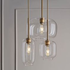 three clear glass pendant lights hanging from a ceiling fixture in a room with white walls