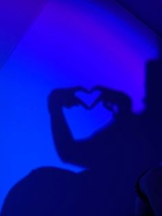 the shadow of a person holding a cell phone in front of a purple and blue background