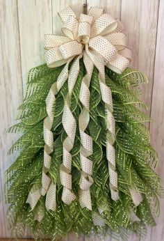 a green and white wreath hanging on the side of a wooden wall with a bow