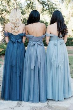 three bridesmaids in blue dresses looking at each other with their backs to the camera