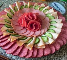 a platter filled with sliced meats and veggies on top of a table