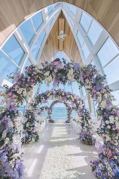 an outdoor ceremony setup with flowers and petals on the aisle leading to the beach side