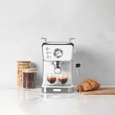 an espresso machine sitting next to some croissants on a counter