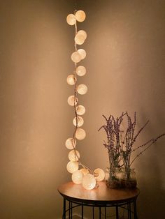 a table topped with a vase filled with flowers next to a string of paper lanterns