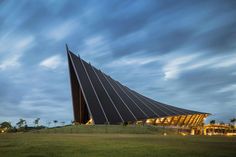 a large triangular building sitting on top of a lush green field under a blue sky