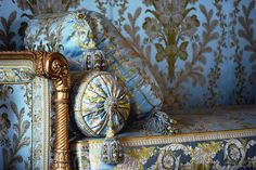 an ornate gold and blue couch with decorative wallpaper