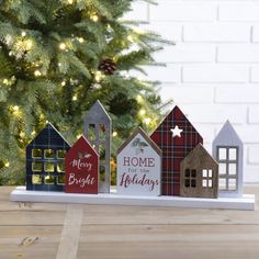 wooden houses are sitting in front of a christmas tree with the words home for the holidays written on them